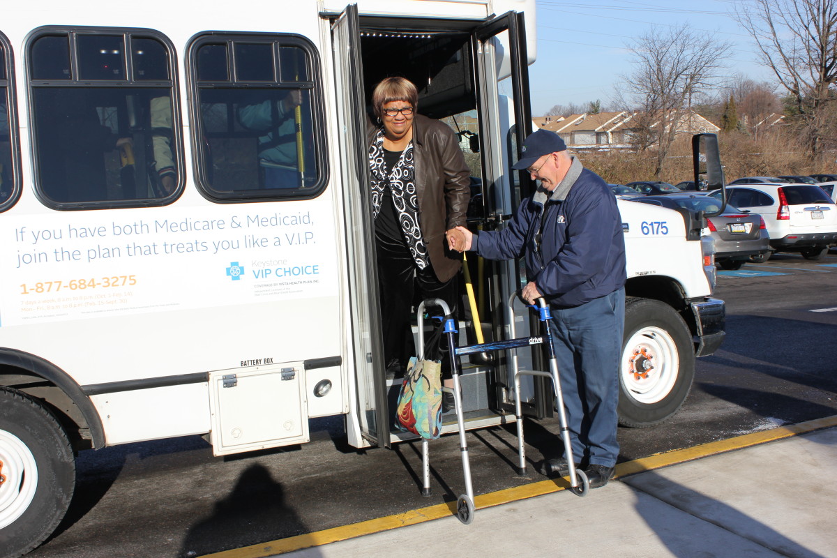 Shared ride driver helps an elderly woman with a walker out of a Shared Ride van.