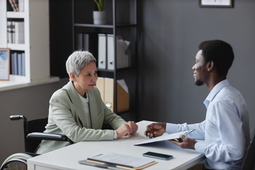 Side view portrait of mature woman with disability speaking to recruiter in job interview
